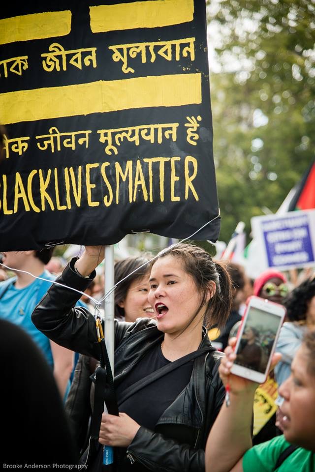 Claudia carrying a banner with the words "Black Lives Matter" written in different Asian languages Photo by Brooke Anderson